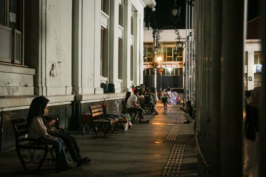 Evening view of a historic street in Bandung, showcasing the vibrant urban nightlife with people and classic architecture.