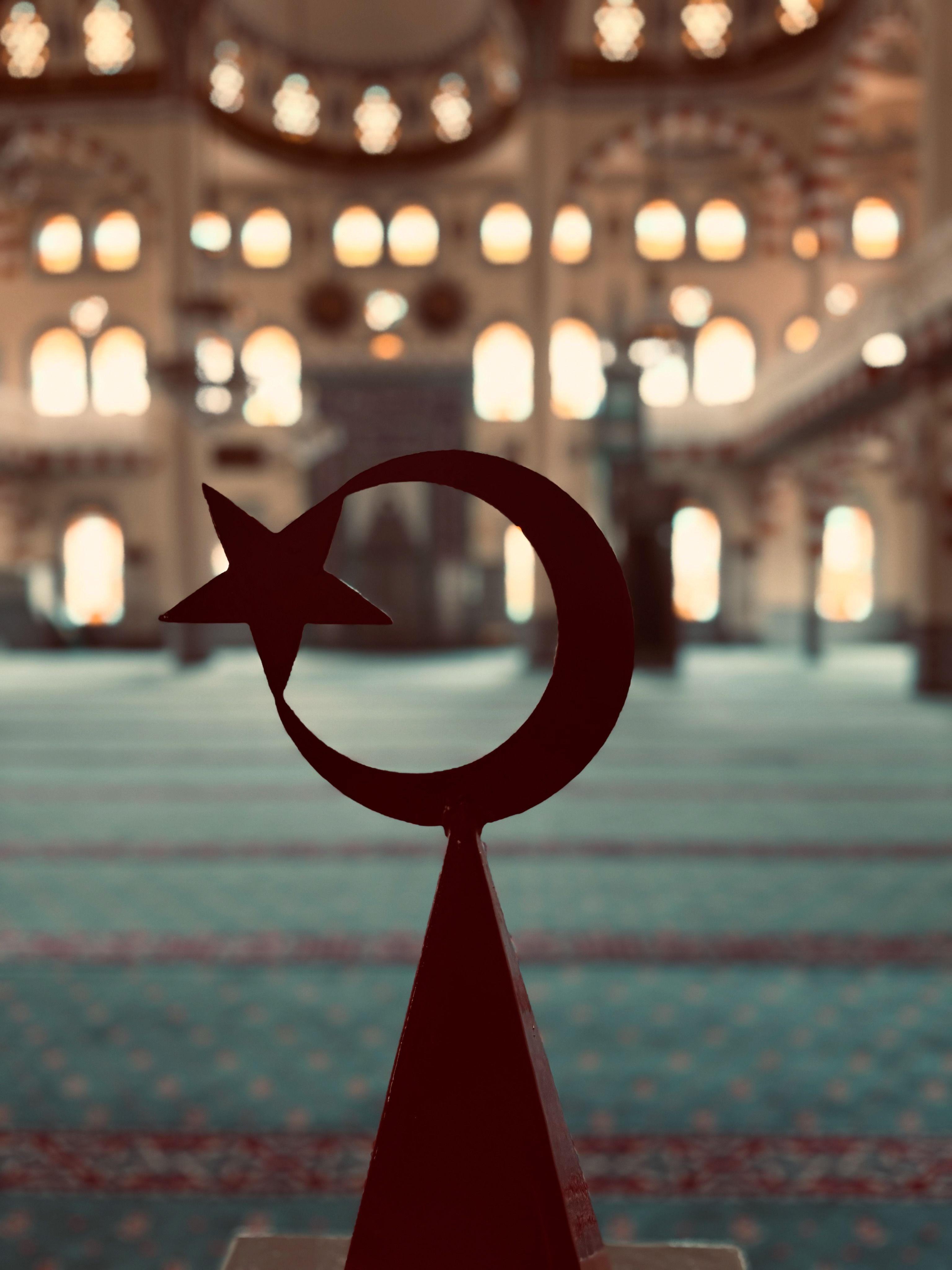 Star and crescent silhouette in a mosque with blurred ornate architecture in the background.