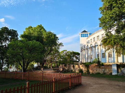 Free A white building surrounded by lush green trees and clear blue sky, creating a serene outdoor scene. Stock Photo