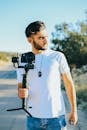 阳光下，一名年轻人手持相机稳定器站在户外