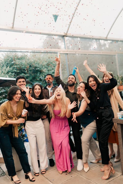 Free A joyful group of friends celebrating indoors with laughter and confetti. Stock Photo