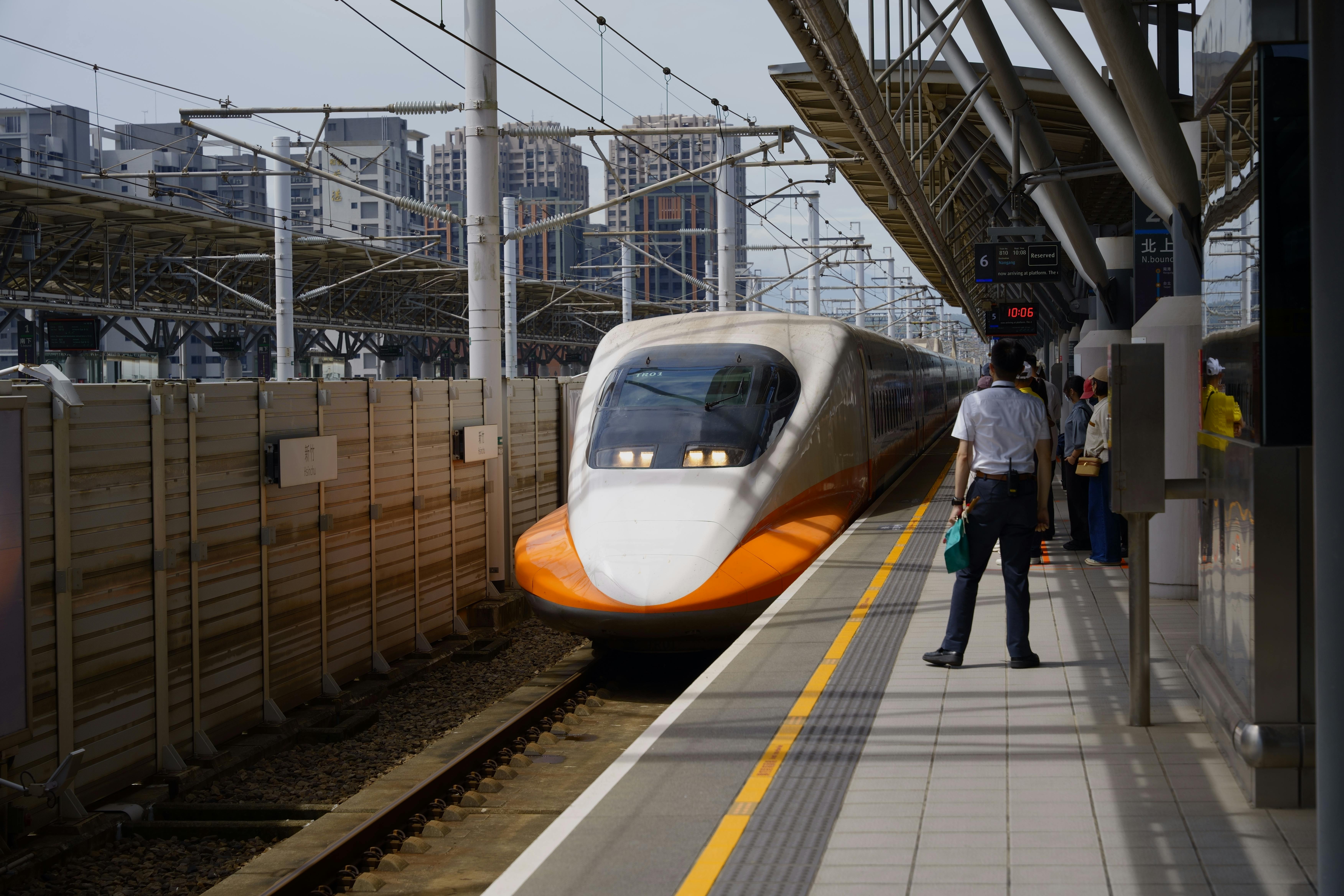 A high-speed train approaches Hsinchu Station in Taiwan on a sunny day.