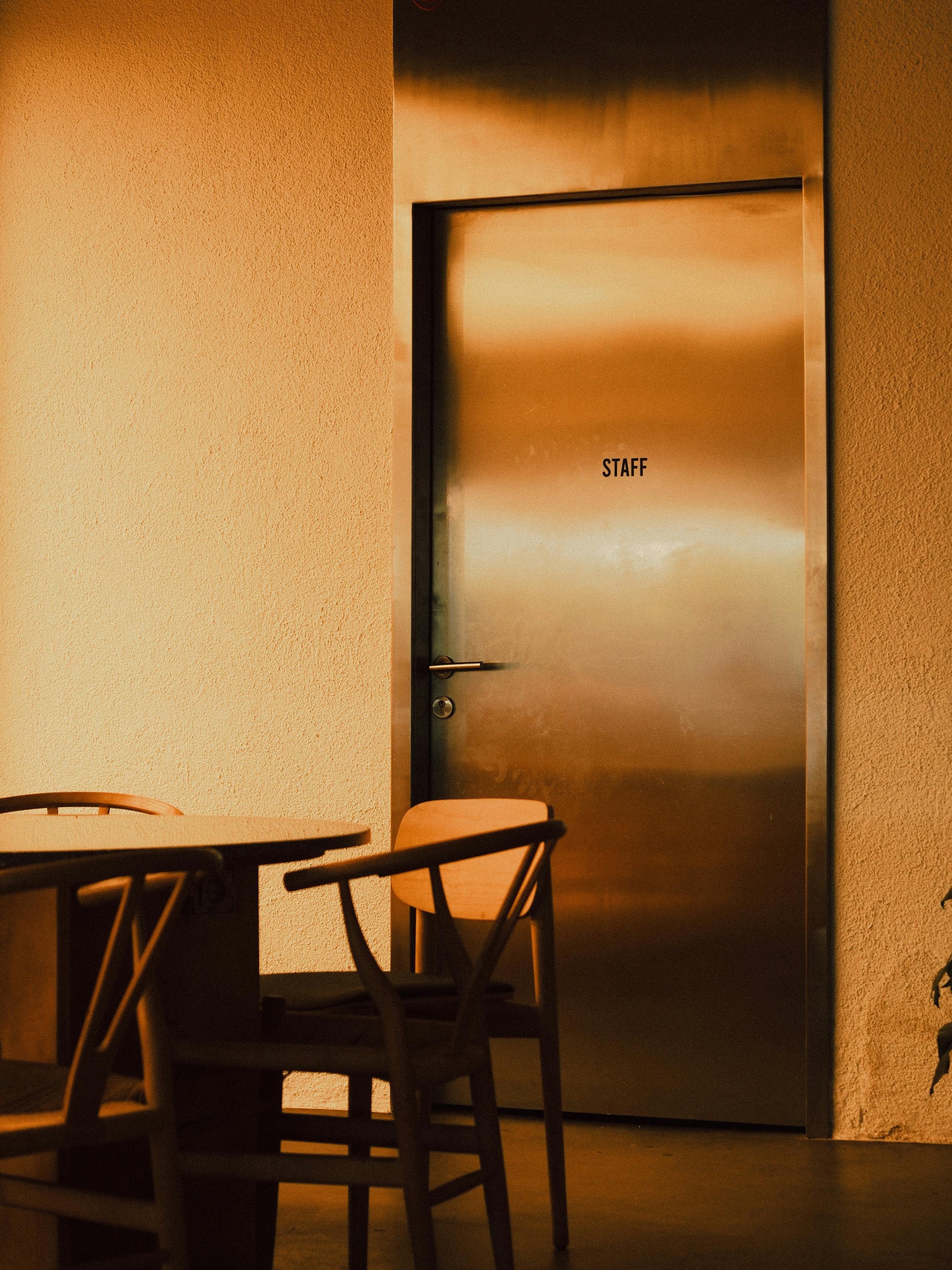 Warm-toned interior featuring a staff-only door and wooden chairs.