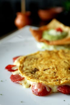 Close-up of a savory Mexican quesadilla with melted cheese and garnish on a plate.