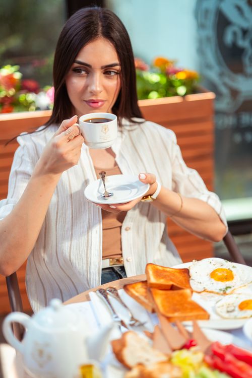 Free Adult enjoying breakfast with tea at a stylish Baghdad cafe. Vibrant outdoor setting. Stock Photo