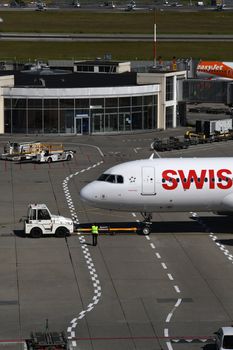 A Swiss airplane being towed at Genève Airport on a clear day.