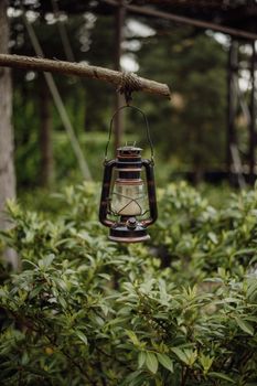 A rustic lantern suspended over green foliage, creating a serene outdoor atmosphere.