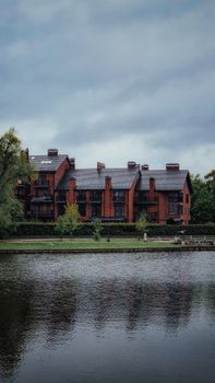 Stunning view of a red brick building surrounded by greenery and a serene lake.