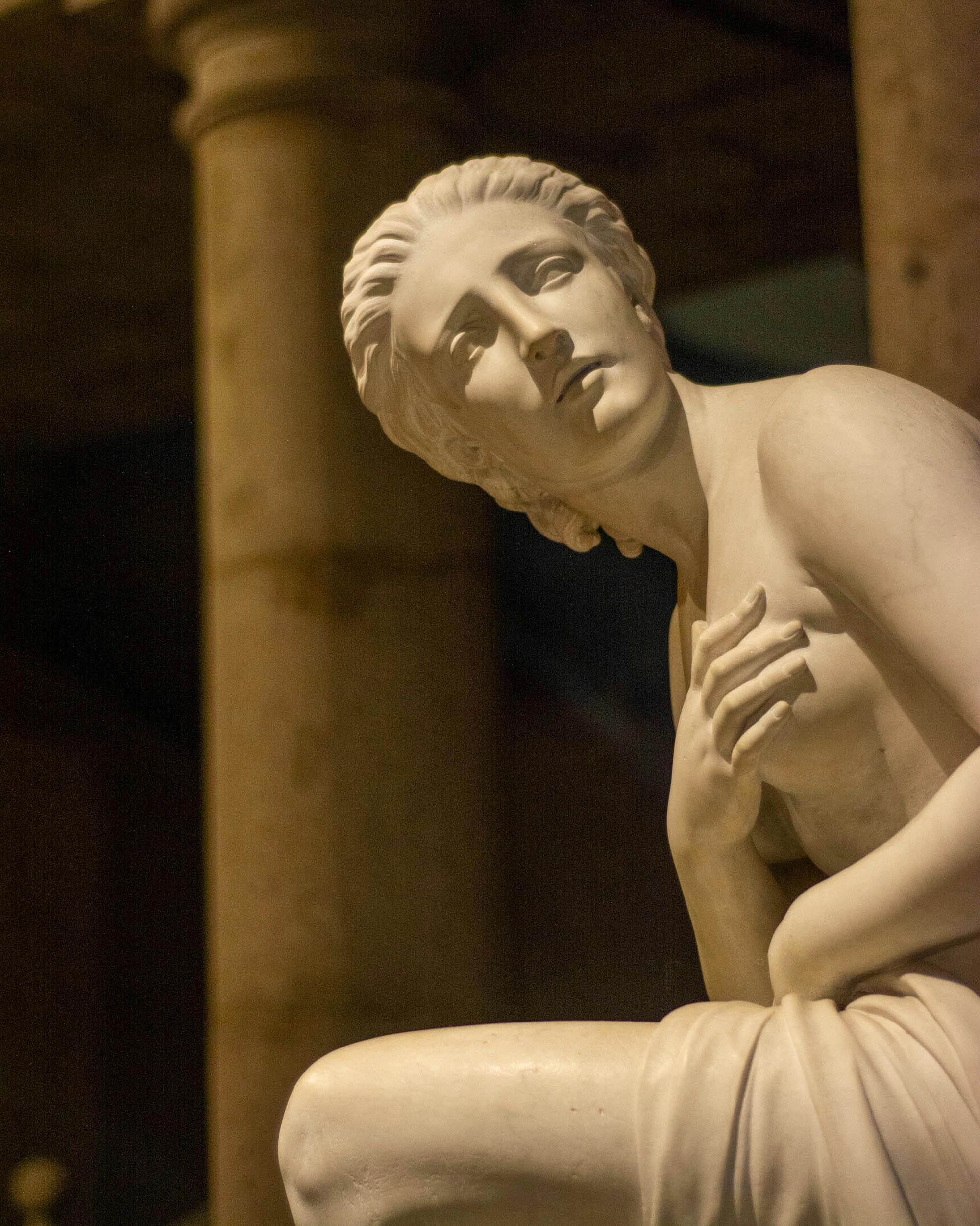 Close-up of an elegant marble statue in a classical architectural setting, evoking timeless beauty.