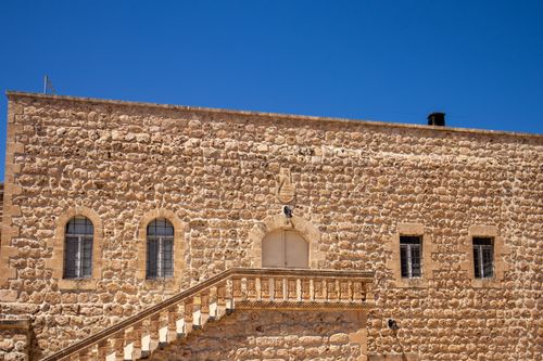 Free A historic stone building in Mardin, Türkiye, with traditional architecture under a clear blue sky. Stock Photo