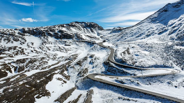 A stunning aerial view of a winding snowy road through the mountains in Kärnten, Austria.