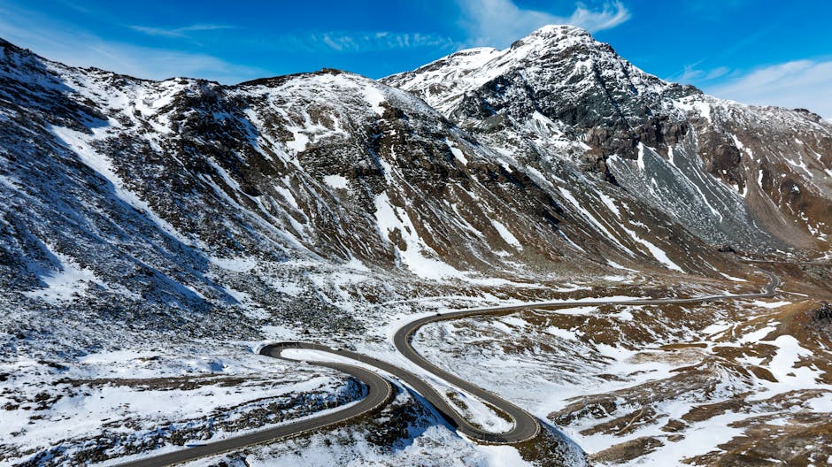 A breathtaking view of a winding high-altitude road through the snowy Austrian Alps, perfect for adventure enthusiasts.