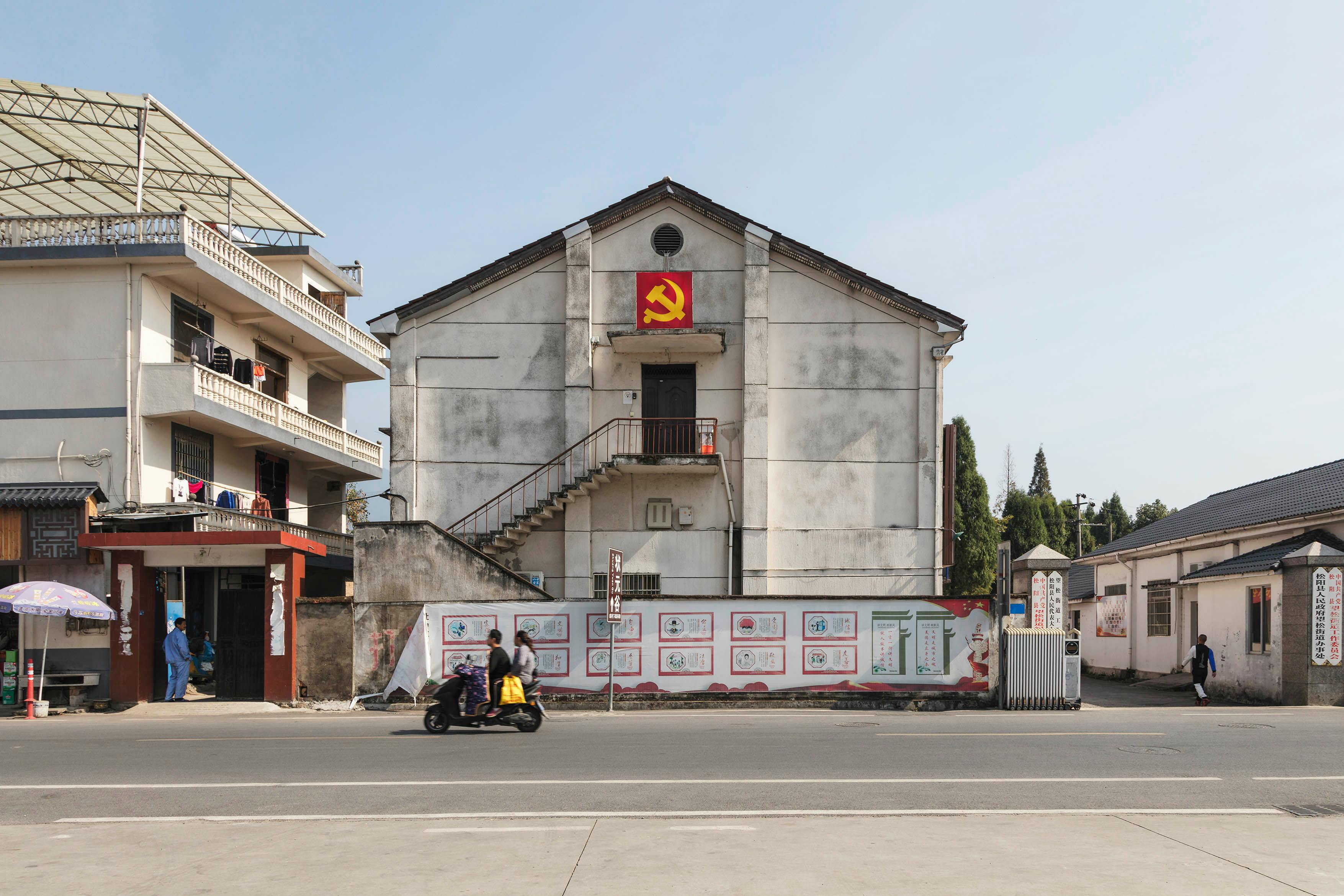 Exteriors of low level buildings decorated with hammer and sickle flag located in suburban area in Communist country