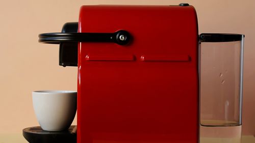 Free Red coffee machine with a white ceramic mug, ideal for coffee lovers and modern kitchens. Stock Photo