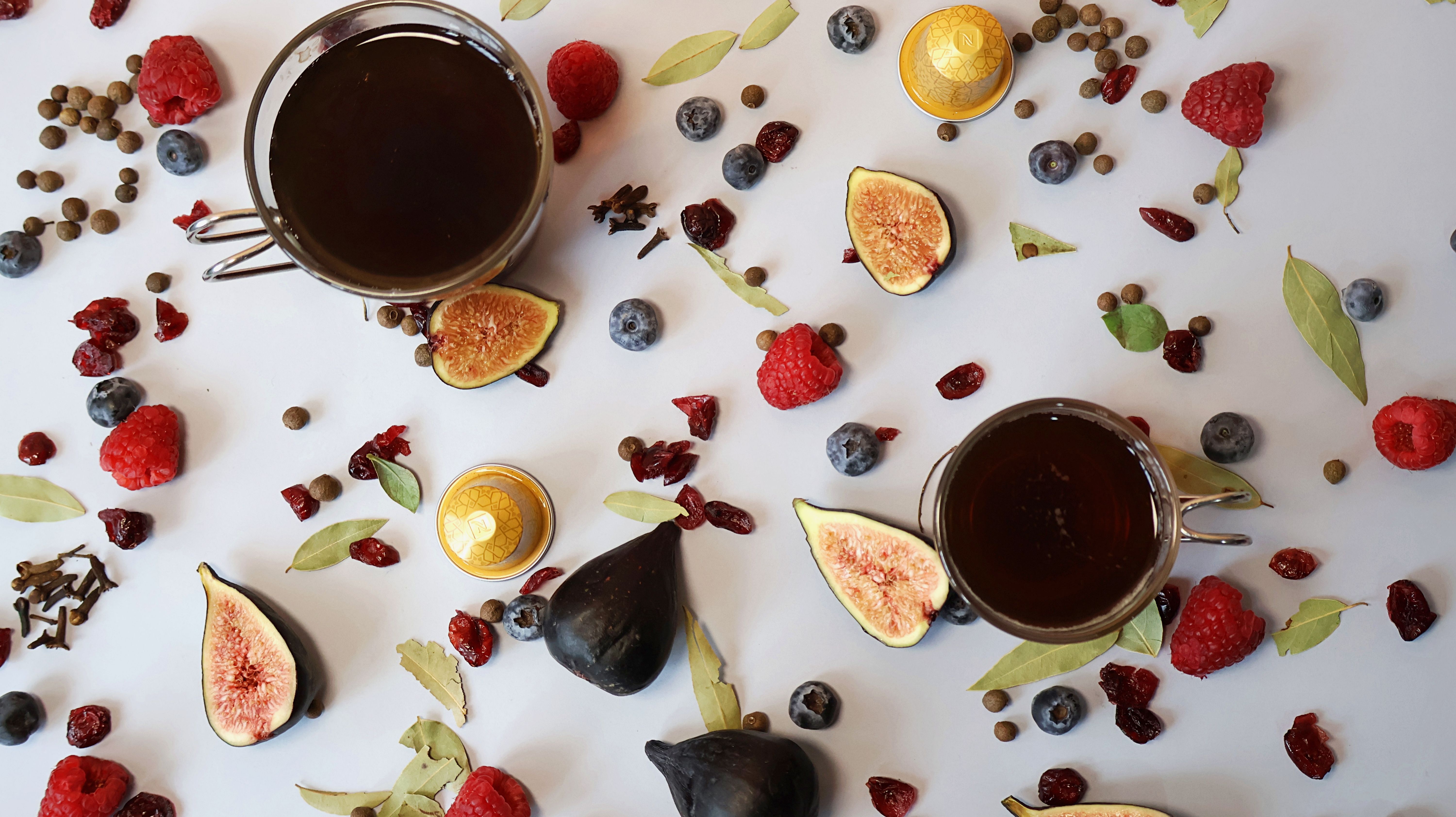 A captivating flat lay showcasing coffee, figs, berries, and spices on a white background.