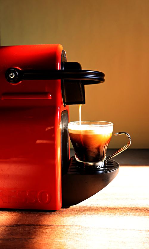Free A striking red espresso machine brewing a fresh cup, capturing a warm cafe ambiance. Stock Photo