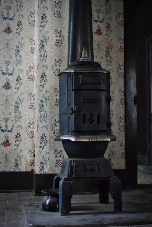 Free Vintage cast iron stove with floral wallpaper creates a rustic atmosphere. Stock Photo