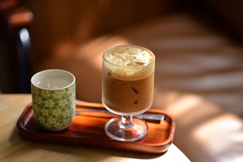 Free Chilled iced coffee served with a floral cup on a wooden tray, basking in natural light. Stock Photo