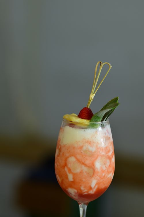 Refreshing strawberry coconut rum punch in a tall glass garnished with fresh tropical fruit