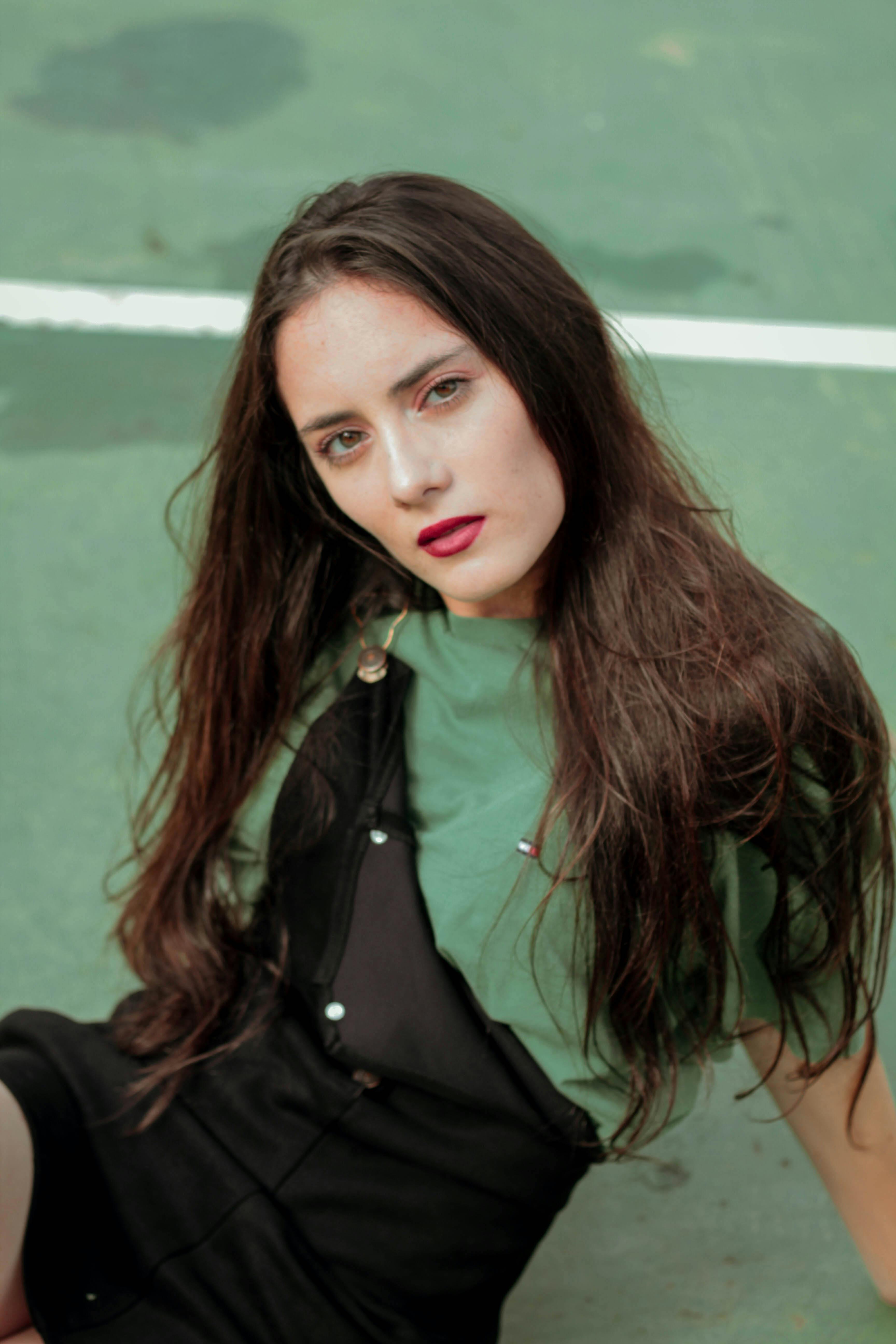 一位长发女子身着休闲装，坦率地坐在球场上