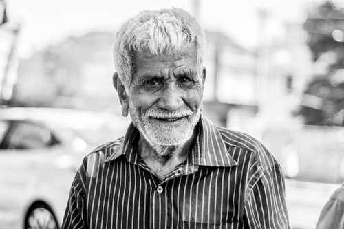 Free A candid black and white portrait of a smiling elderly man outdoors, capturing warmth and character. Stock Photo