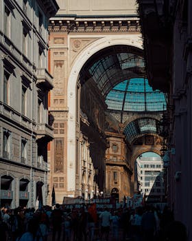 Crowds gather under the historic arch of Galleria Vittorio Emanuele II in Milan, Italy.