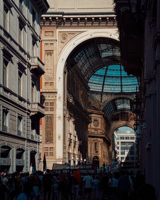 Crowds gather under the historic arch of Galleria Vittorio Emanuele II in Milan, Italy.