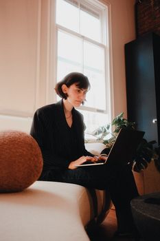 Woman in modern home office working on a laptop with natural light.