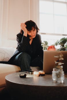 Young woman focused on work at her laptop in a cozy home setting.