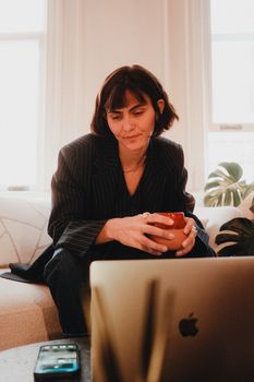 Relaxed businesswoman with coffee mug working from home office.