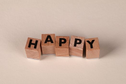 Wooden blocks with the word 'Happy' on a light neutral background. Perfect for themes of joy and positivity.