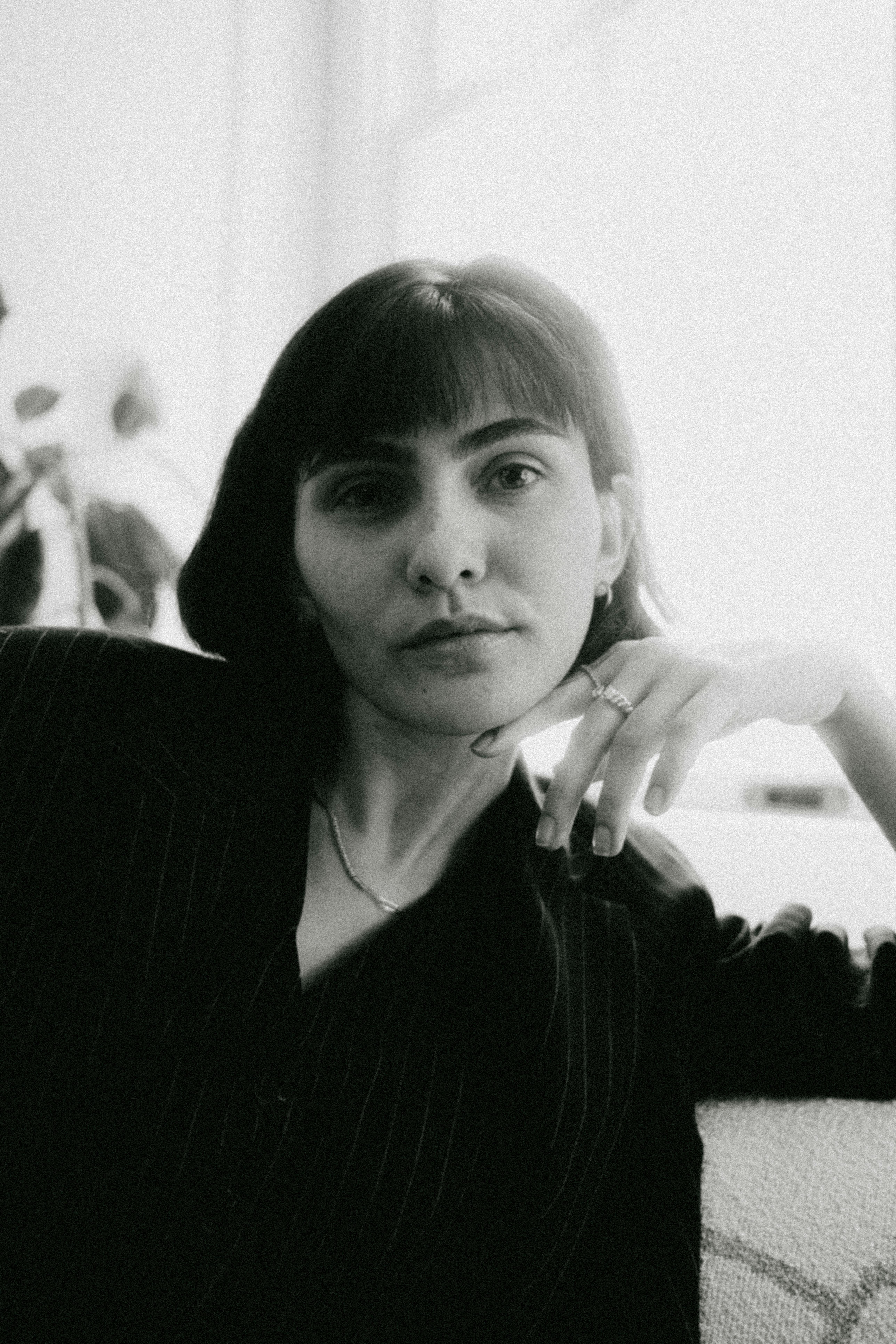 Black and white portrait of a woman sitting indoors with a serene expression.