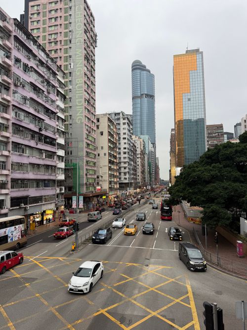 Free Busy urban street in Hong Kong with tall buildings and heavy traffic under gray skies. Stock Photo