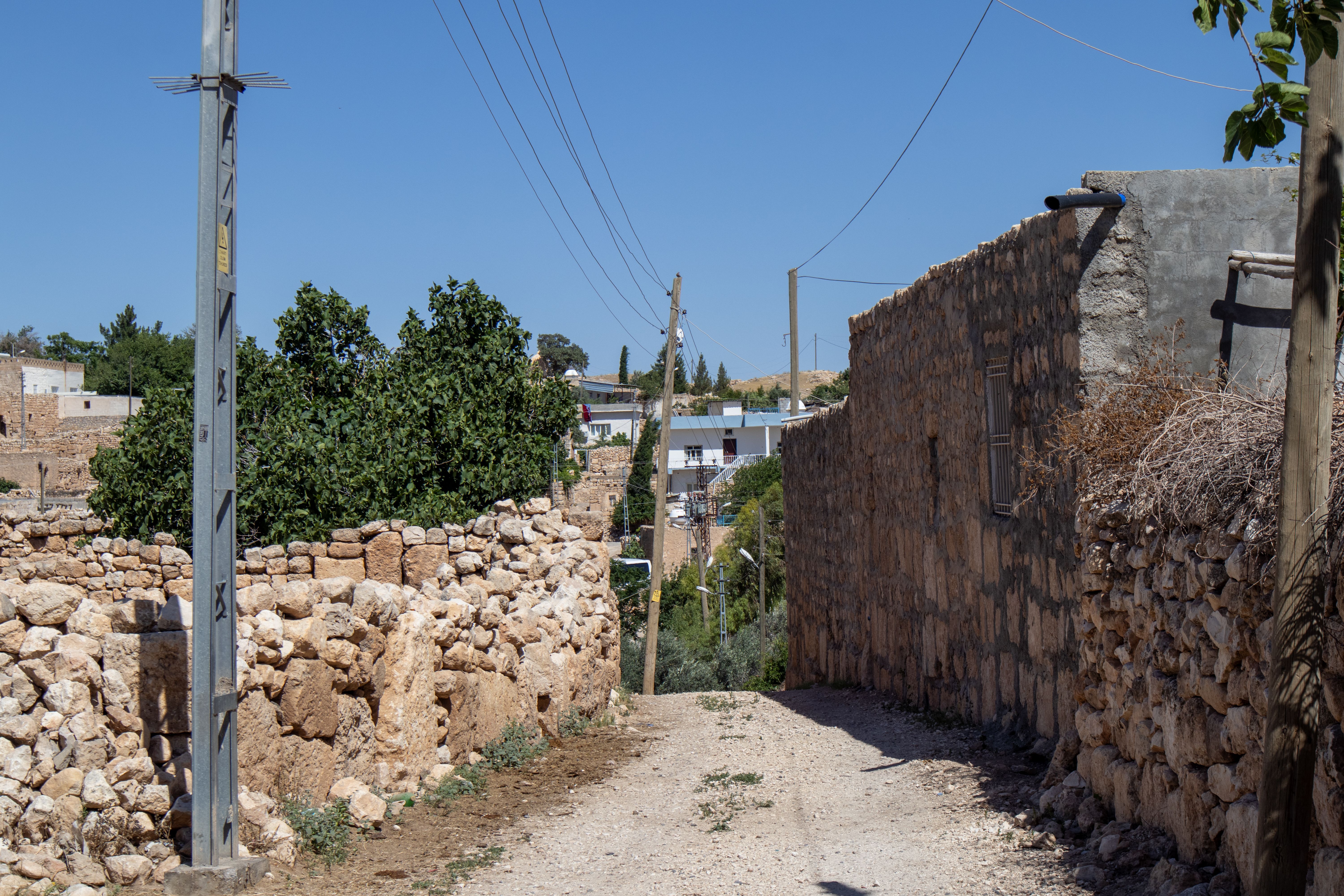 Charming rustic street in Mardin, Turkey, showcasing typical stone architecture under a clear blue sky.
