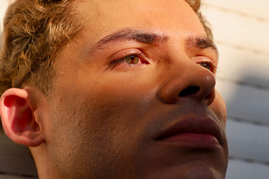 太陽の光が顔に影を落としている若い男性のクローズアップ。