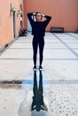 一位穿着休闲装的年轻女子站在院子里的反光水坑旁