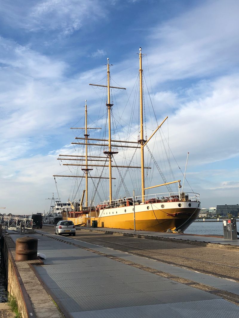 Tall ship docked at a harbour on a clear day showing its masts and rigging