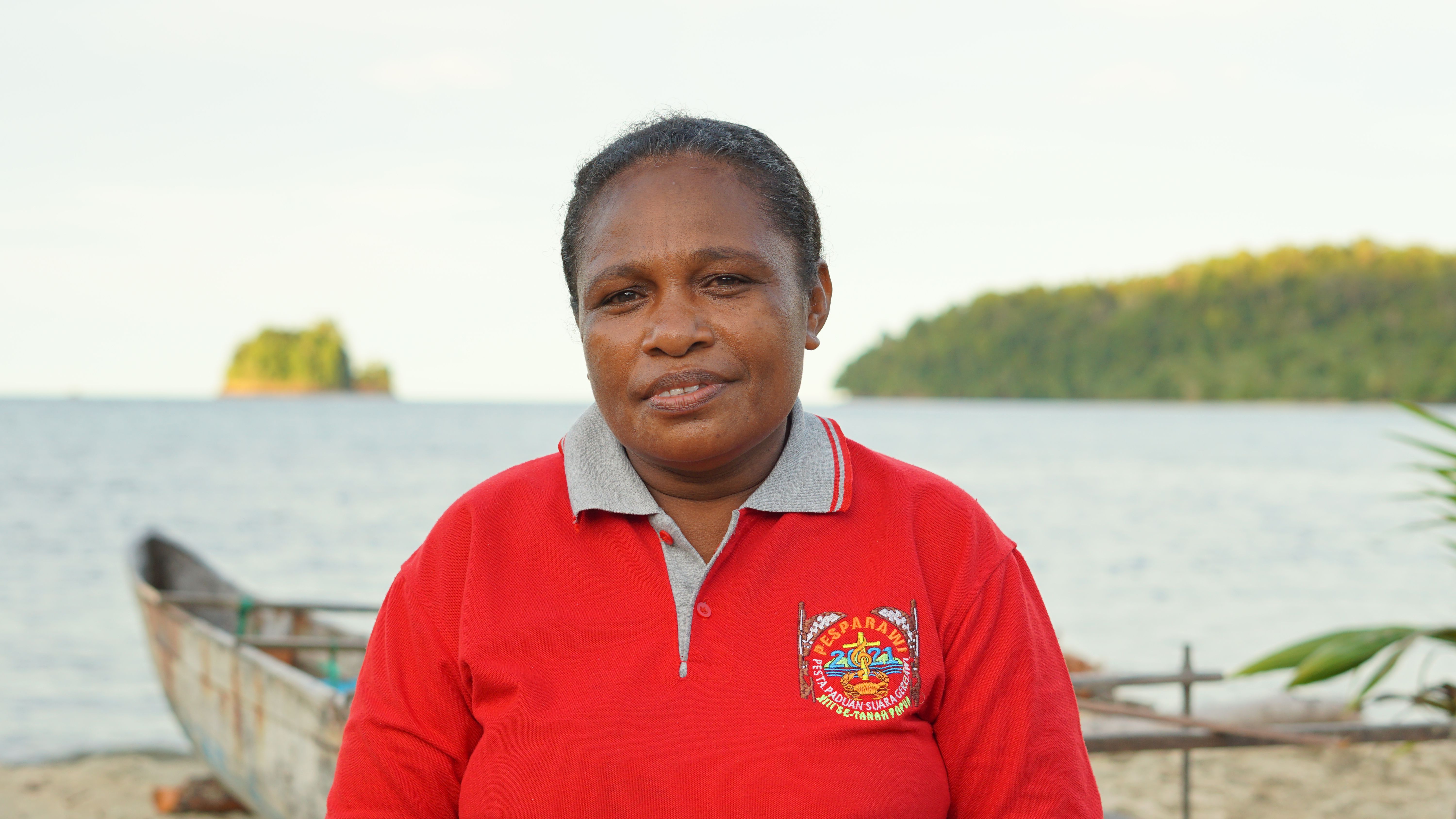 A Papuan woman in traditional attire by the beach in Papua, Indonesia.