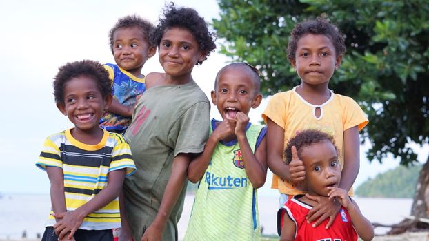 A group of smiling Papuan children enjoying a bright day outdoors in Papua, Indonesia.