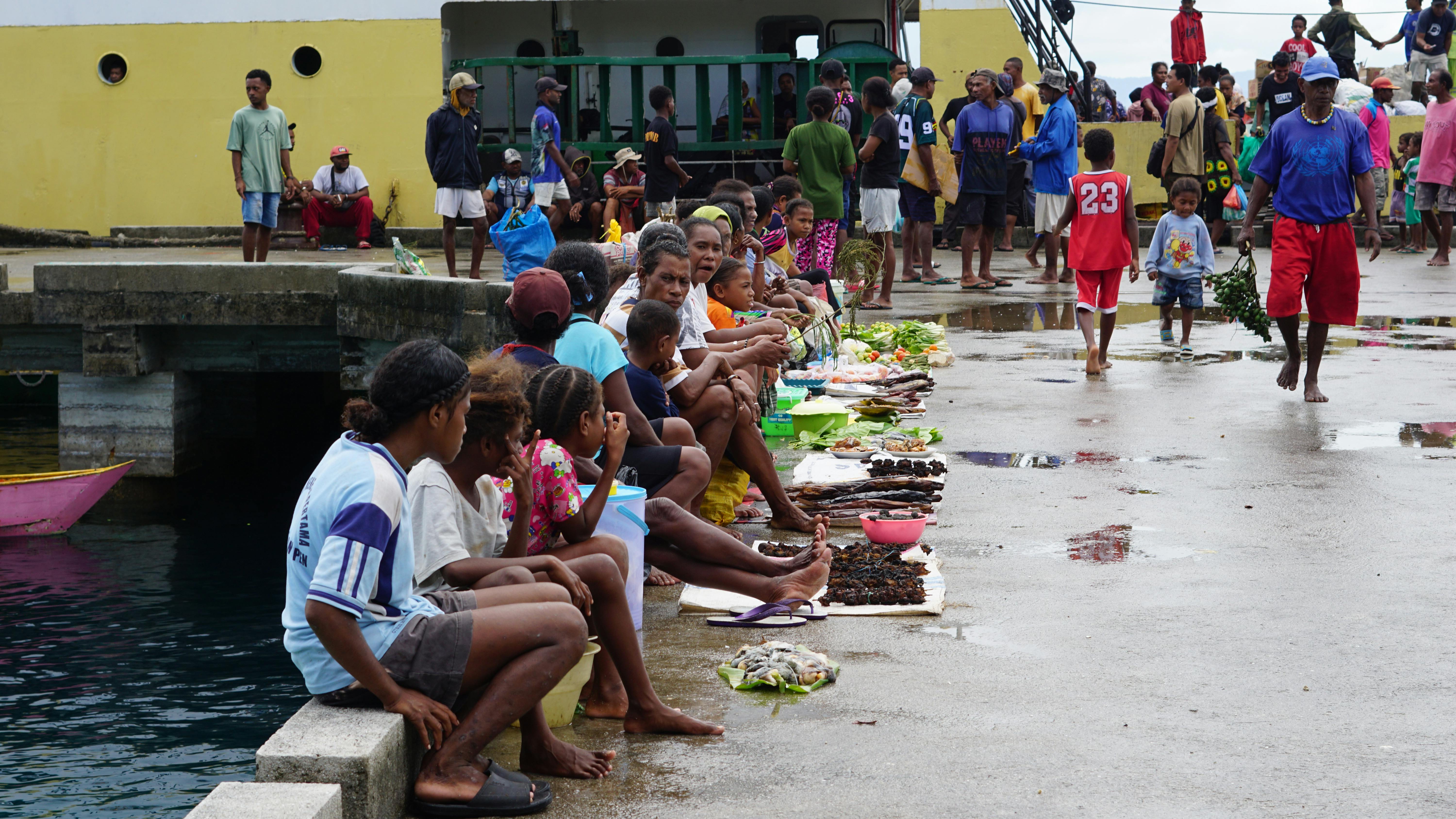 A bustling market scene with locals selling food and goods in Papua, Indonesia.
