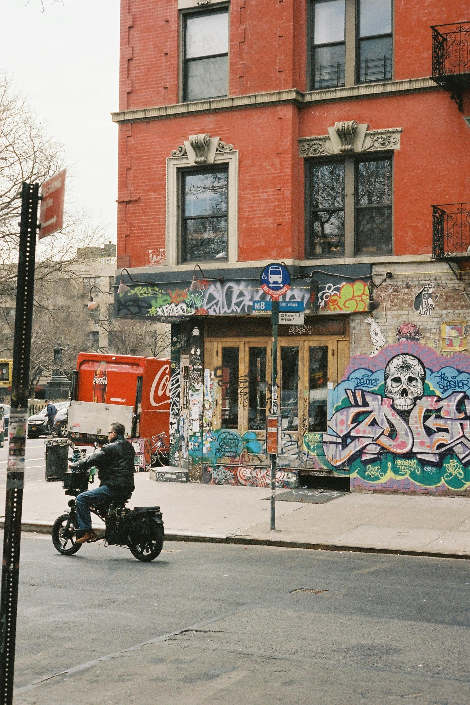 Vibrant street scene featuring graffiti art and a motorcycle rider on a city sidewalk.