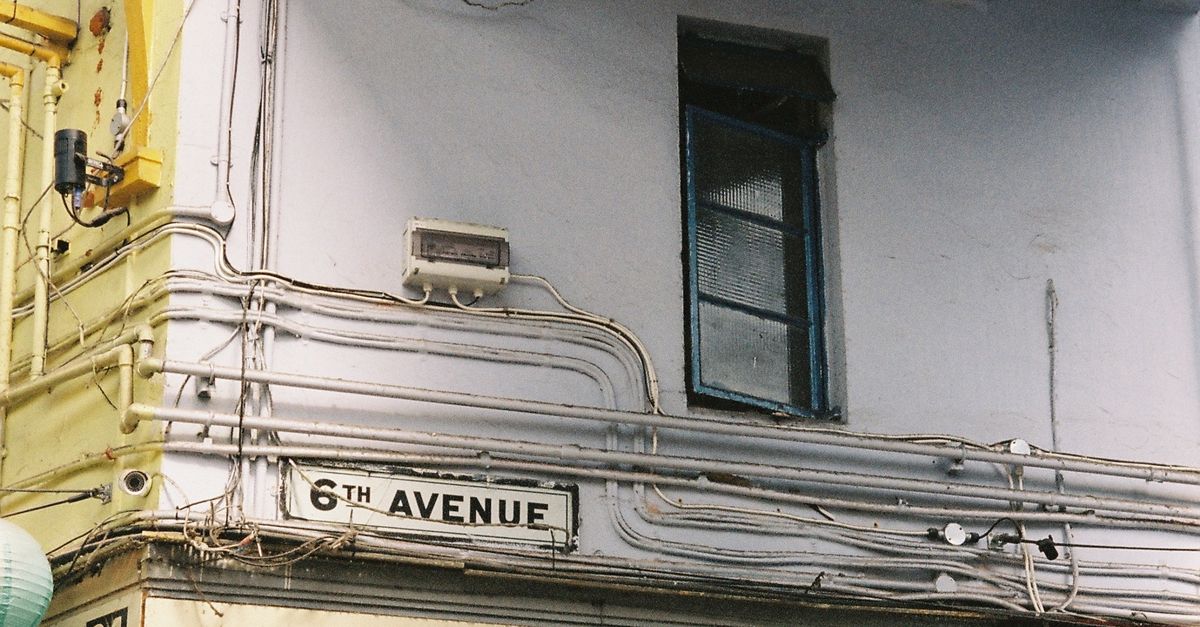 Street view of a corner building with Latin American products signage on 6th Avenue.