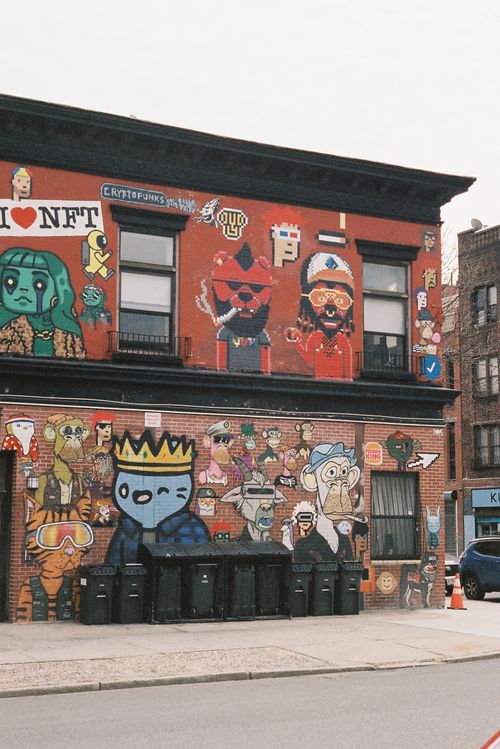 Free Colorful street art featuring various characters and NFT designs on a brick building. Stock Photo