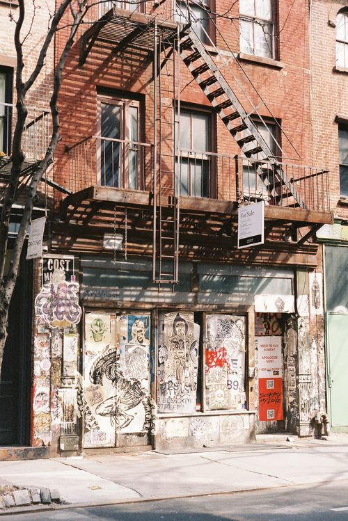 Free A city street scene featuring vibrant graffiti on a brick building's facade with a fire escape. Stock Photo