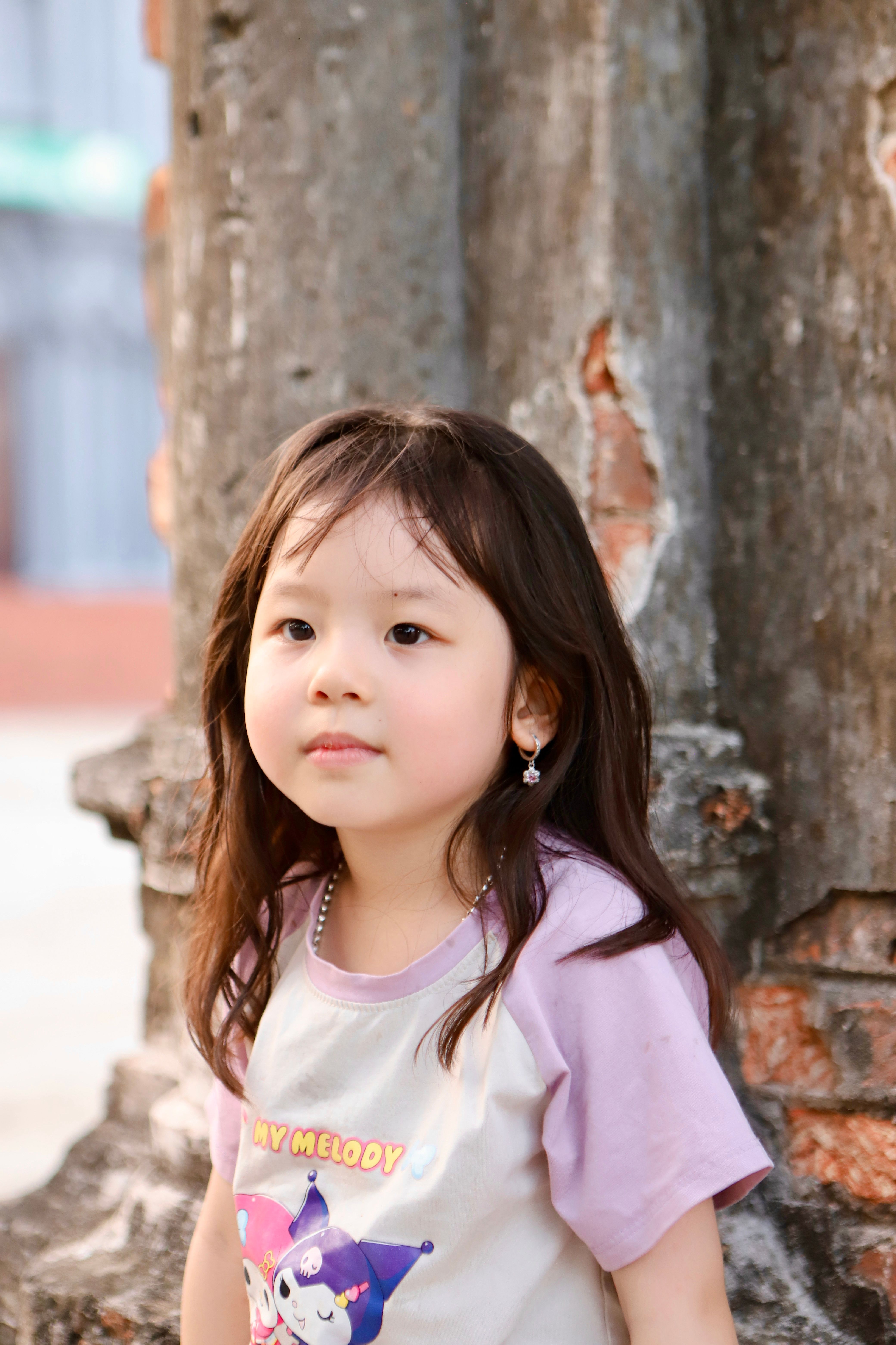 Adorable Vietnamese child posing outdoors against rustic architecture in Hai Duong.