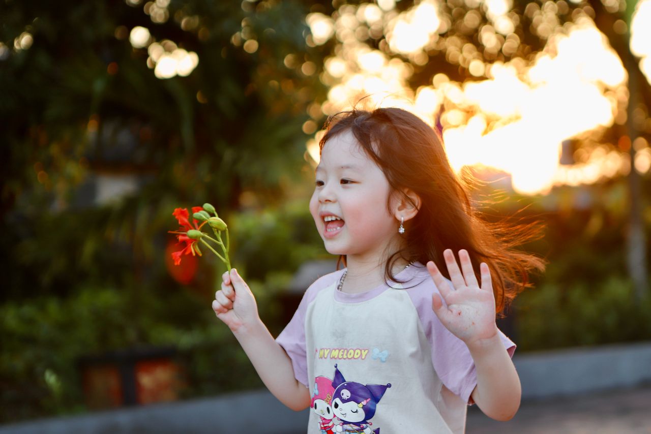 a happy child holding flowers in a vibrant outdoor setting during suns