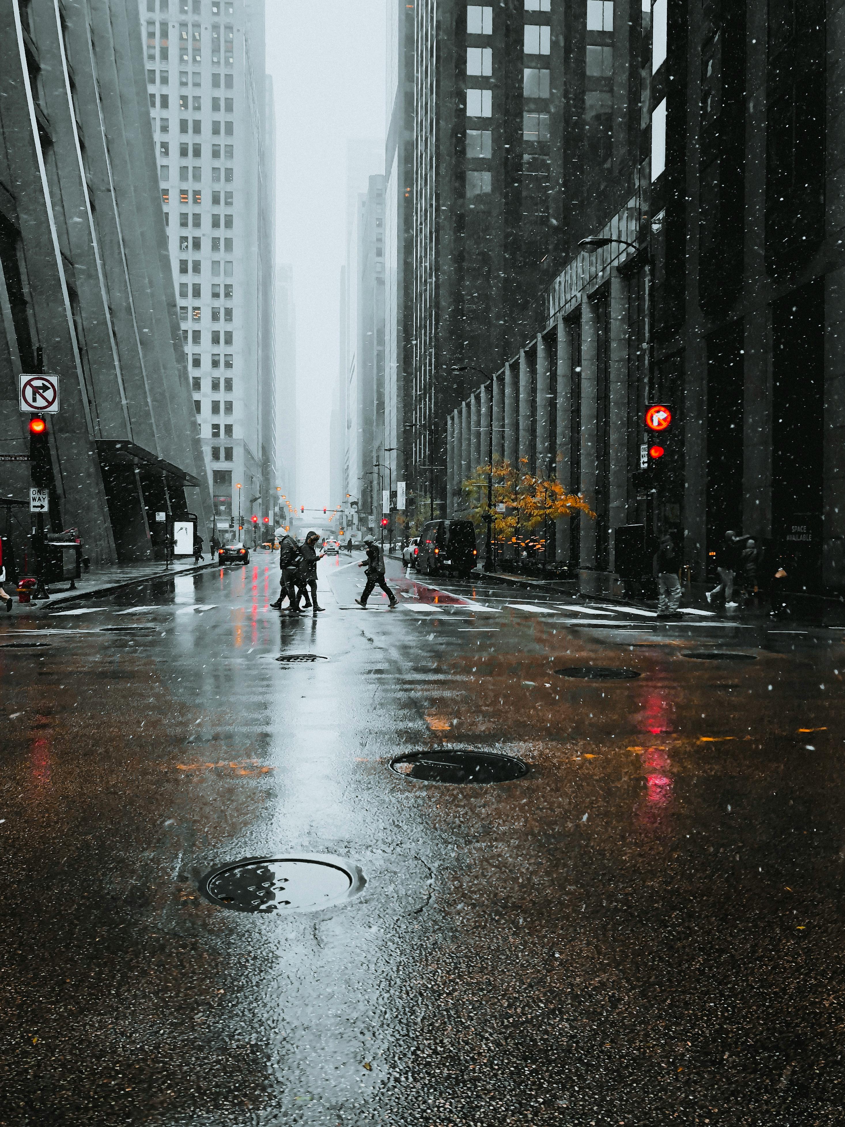 雨天，城市里的行人穿过高楼与红绿灯间潮湿的街道