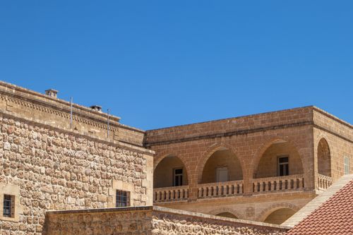 Free Sunlit view of traditional stone architecture in Mardin, Türkiye with clear blue skies. Stock Photo