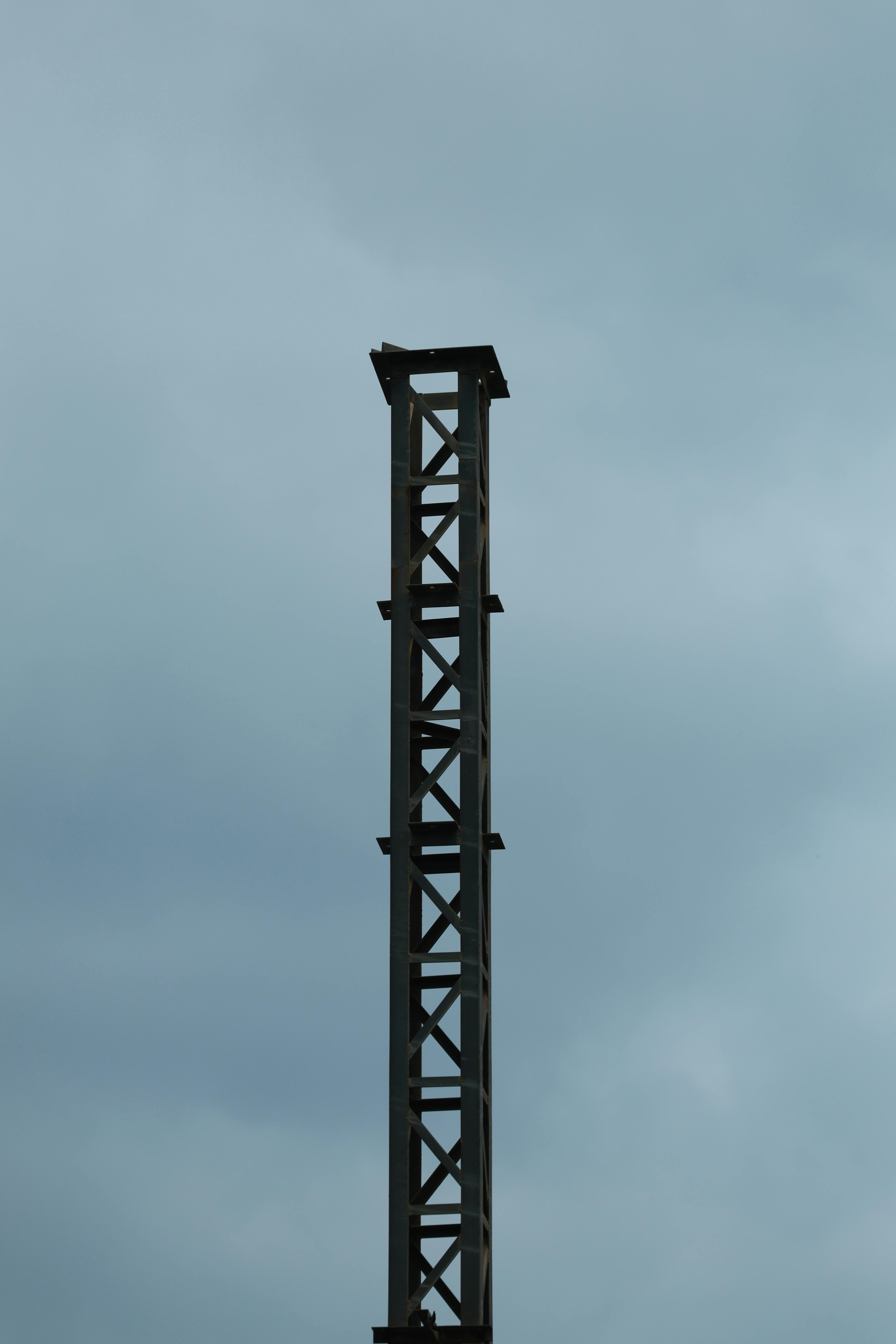 Kostenlos Eine hoch aufragende Metallstruktur vor einem bewölkten Himmel schafft eine minimalistische Industrieszene. Stock-Foto