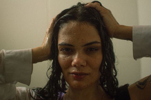 Free Close-up portrait of a woman with wet hair in a thoughtful pose, conveying a moody atmosphere. Stock Photo